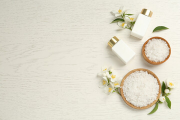 Fototapeta na wymiar Beautiful jasmine flowers, skin care products and sea salt on white wooden table, flat lay. Space for text
