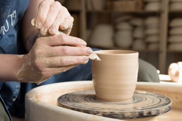 hands of a potter making ceramic mug from clay on pottery wheel