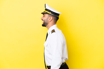 Airplane arab pilot man isolated on yellow background laughing in lateral position