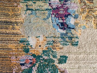 Fragment of a vintage woolen rug with a floral pattern and scuffs