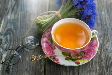 Summer still life with a cup of tea, a book and a bouquet of cornflowers.