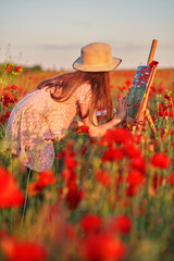 Little girl is standing in the field of red poppies