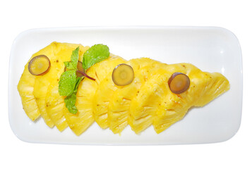 Pineapple dessert with pieces of grapes and mint on a white saucer on a white plate