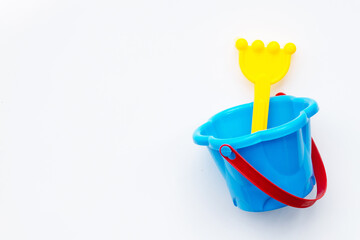 Plastic toys, shovel in bucket for sand on white surface.
