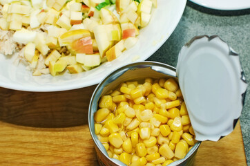 Adding canned corn to vegetable salad.