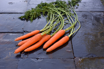 Fresh organic carrots on a wet slate background