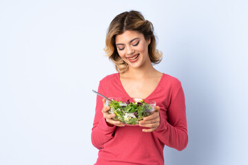 Teenager woman with salad isolated on blue background