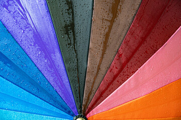 Wet surface of rainbow umbrella under drizzle rain. Drops dripping at bright umbrella. Rainy...