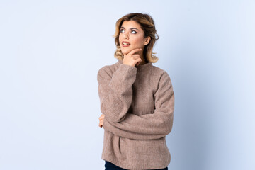 Young Russian woman isolated on blue background having doubts while looking up