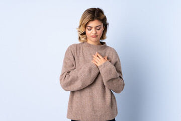 Young Russian woman isolated on blue background having a pain in the heart