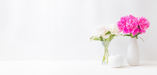 Minimalist home interior with decor elements. Pink peonies in a vase on a light background