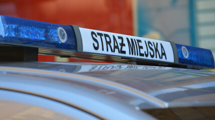 Znak straż miejska na dachu radiowozu  polskiej policji.