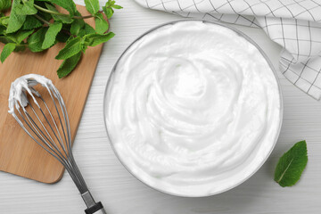 White cream, balloon whisk and mint on wooden table, flat lay