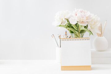 Mockup desk calendar and white peonies in a vase on a light background