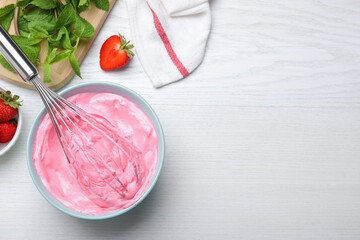 Strawberry cream with balloon whisk on white wooden table, flat lay. Space for text