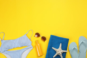 Flat lay composition with beach objects on yellow background, space for text