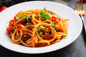 Spaghetti alla puttanesca - italian pasta dish with tomatoes, black olives, capers, anchovies and parsley.