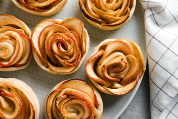 Obraz na płótnie Canvas Freshly baked apple roses on grey table, flat lay. Beautiful dessert