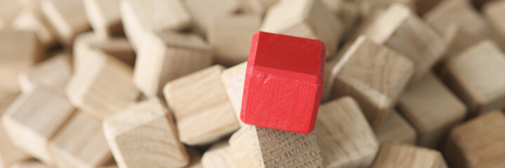 Wooden cubes of beige color in middle there is red cube