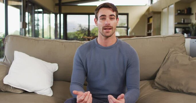 Portrait of caucasian man talking looking that camera sitting on the couch at vacation home