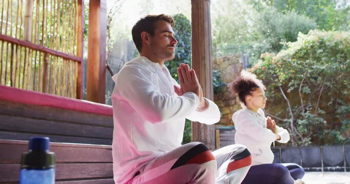 Mixed race couple practicing yoga and meditating together at vacation home