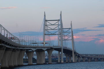 Close-up of the cable bridge and the motorway over the bay against the evening sky with red reflexes from the setting sun, "No stopping on the Autobahn" sign