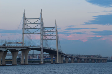 Obraz premium Close-up of the cable bridge and the motorway over the bay against the evening sky with red reflexes from the setting sun, 