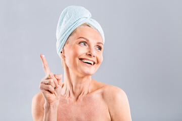 Senior smiling 50s middle aged mature older woman applying facial cream on face looking at camera isolated over white background. Anti age healthy dry skin care beauty therapy concept