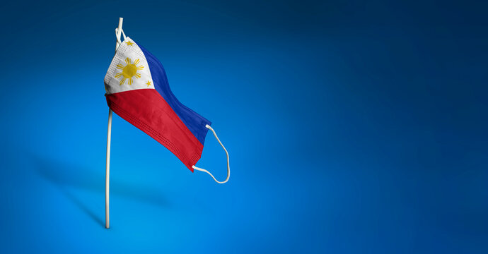 Philippinian mask on dark blue background. Waving flag of the Philippines painted on medical mask on pole. Concept of The banner of the fight against the epidemic coronavirus COVID-19