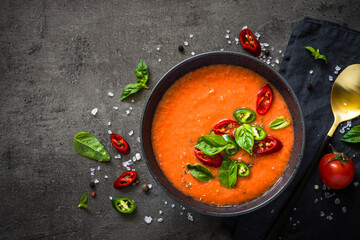 Tomato soup or gazpacho soup at black table. Vegan dish. Top view with copy space.