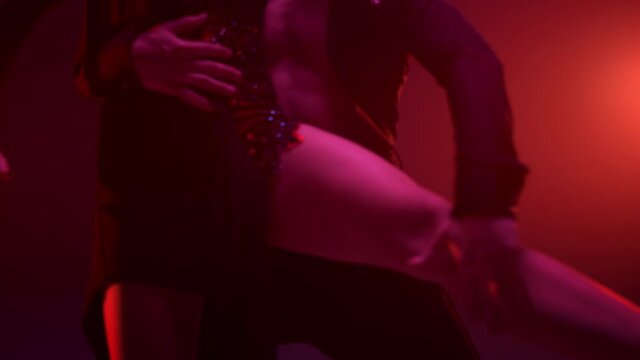Unknown couple feet dancing in dark hall. Sensual dancers doing support indoors.
