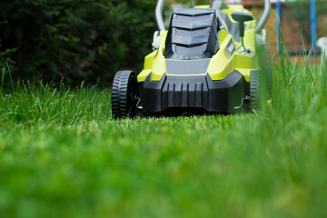Green lawn mower on green grass. Gardening concept.