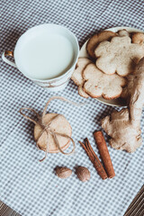 Close up of homemade ginger cookies, cinnamon, ginger with cup of milk on a towel wooden table. Copy space. Retro toned image, flat lay