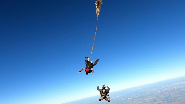 Tandem parachute jump. Instructor with a student and the cameraman taking pictures.