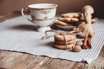 Close up of homemade ginger cookies, cinnamon, ginger with cup of milk on a towel wooden table. Copy space. Retro toned image, flat lay