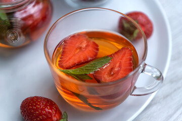 Fruit red tea with strawberries and mint leaves in the summer garden.