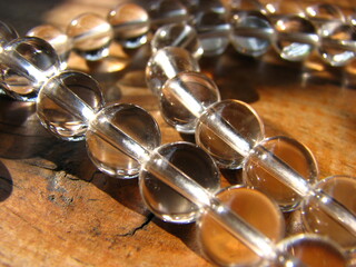 Transparent beads on the thread. Crystal beads lie on a wooden surface
