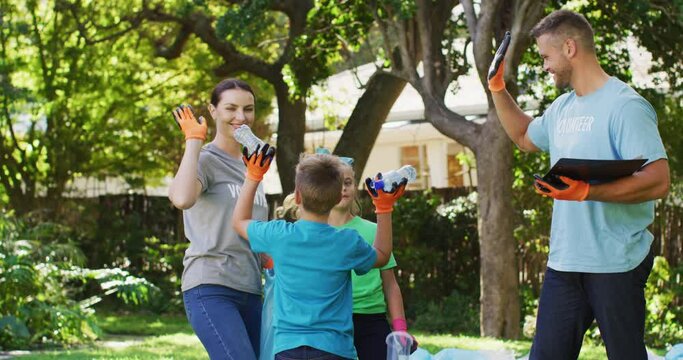 Smiling caucasian parents,son and daughter outdoors collecting plastic waste and high fiving