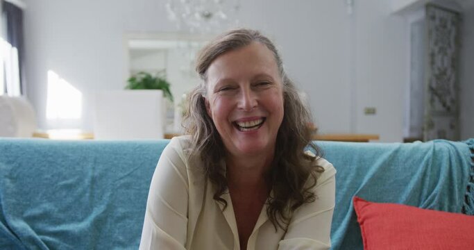 Portrait of happy senior caucasian woman sitting in living room smiling
