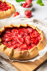 Homemade galettes with strawberries on white marble background