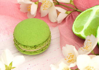 Fototapeta na wymiar green macaroon cake on a pink background with a slice of lime. Lime macaroon with green cream. Round mint dessert. High quality photo