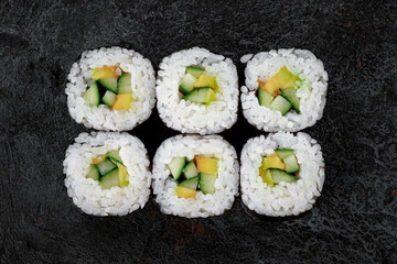 Maki Japanese roll with avocado and cucumber on stone. vegetarian sushi-roll, top view