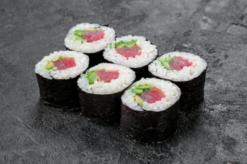 Sake maki Japanese roll with Tuna, cucumber and avocado on stone. Maguro sushi-roll