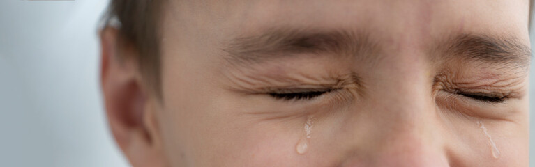 Teardrops rolls down the boy's cheeks, his eyes are closed, he is upset and crying. Sad, unhappy...