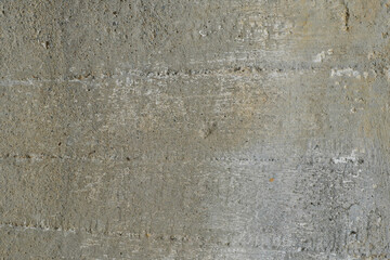 The uneven surface of an old concrete wall with splashes of crushed stone .