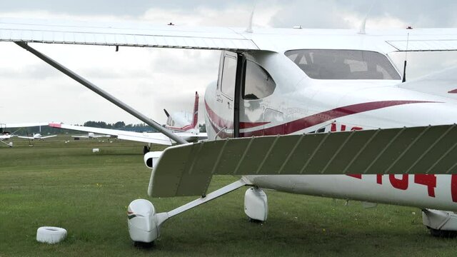 Small high-wing airplane at grass airfield, performing engine startup