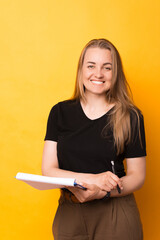 Portrait of smiling woman looking at the camera while making some notes on paper