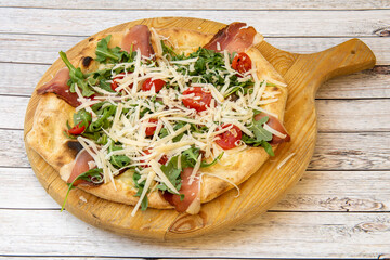 Spring pizza recipe with serrano ham, cherry tomatoes, grated cheese and arugula