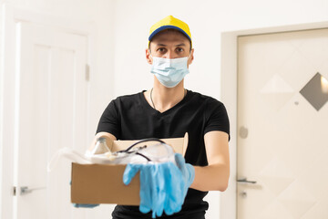 Fototapeta na wymiar hands in blue latex protective gloves hold a moving single open cardboard box containing protective face masks: medical concept, delivery concept, with medical care