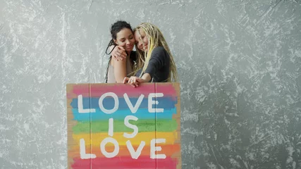 Gardinen Farbenfroh Female lesbian couple holding colorful LGBT poster  © iaginzburg